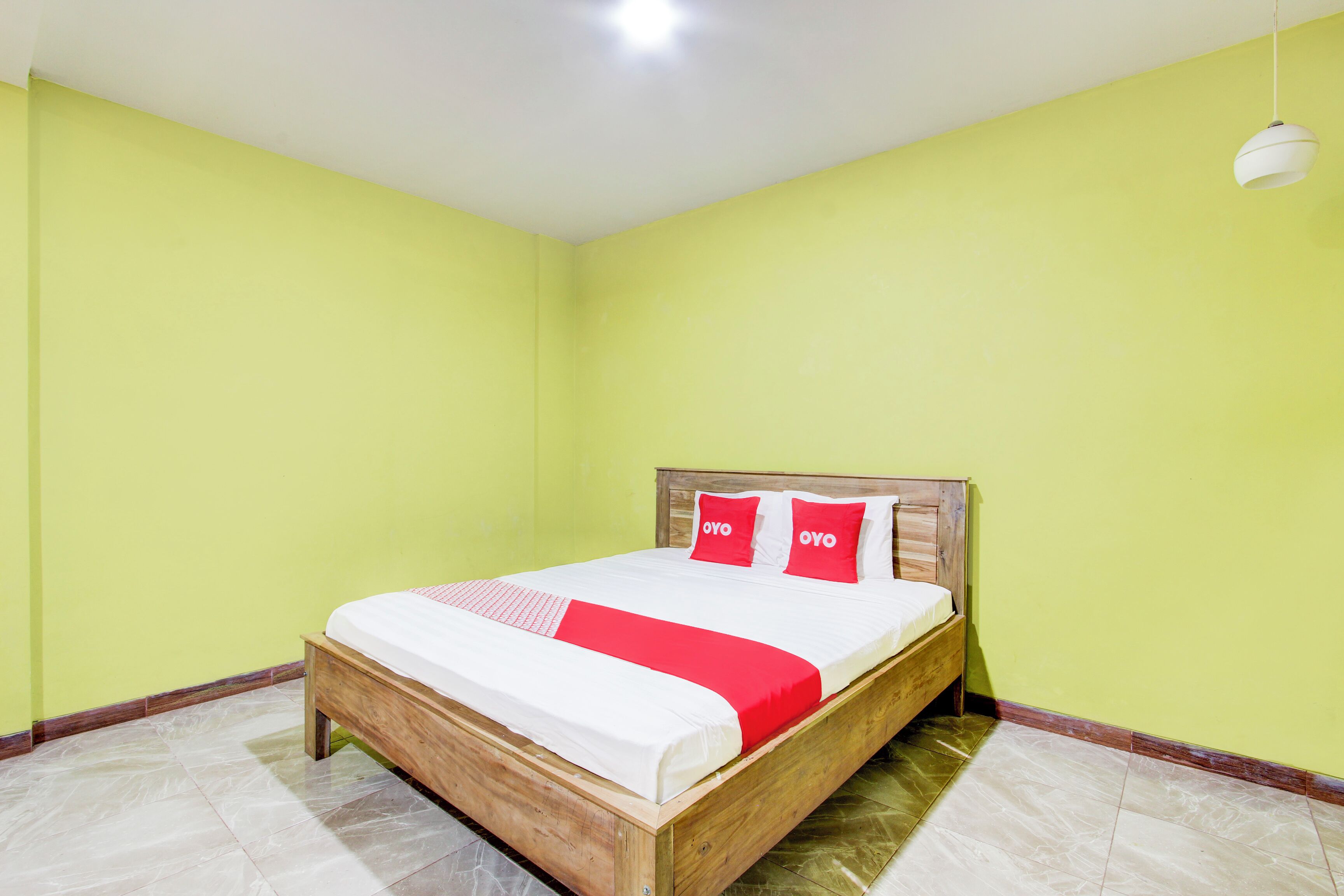 A room with a wooden bed, green walls, and a white ceiling light.