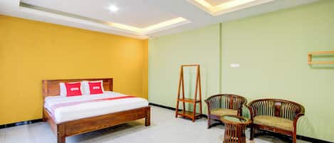 A hotel room with a wooden bed, two chairs, a small table, and a standing mirror.