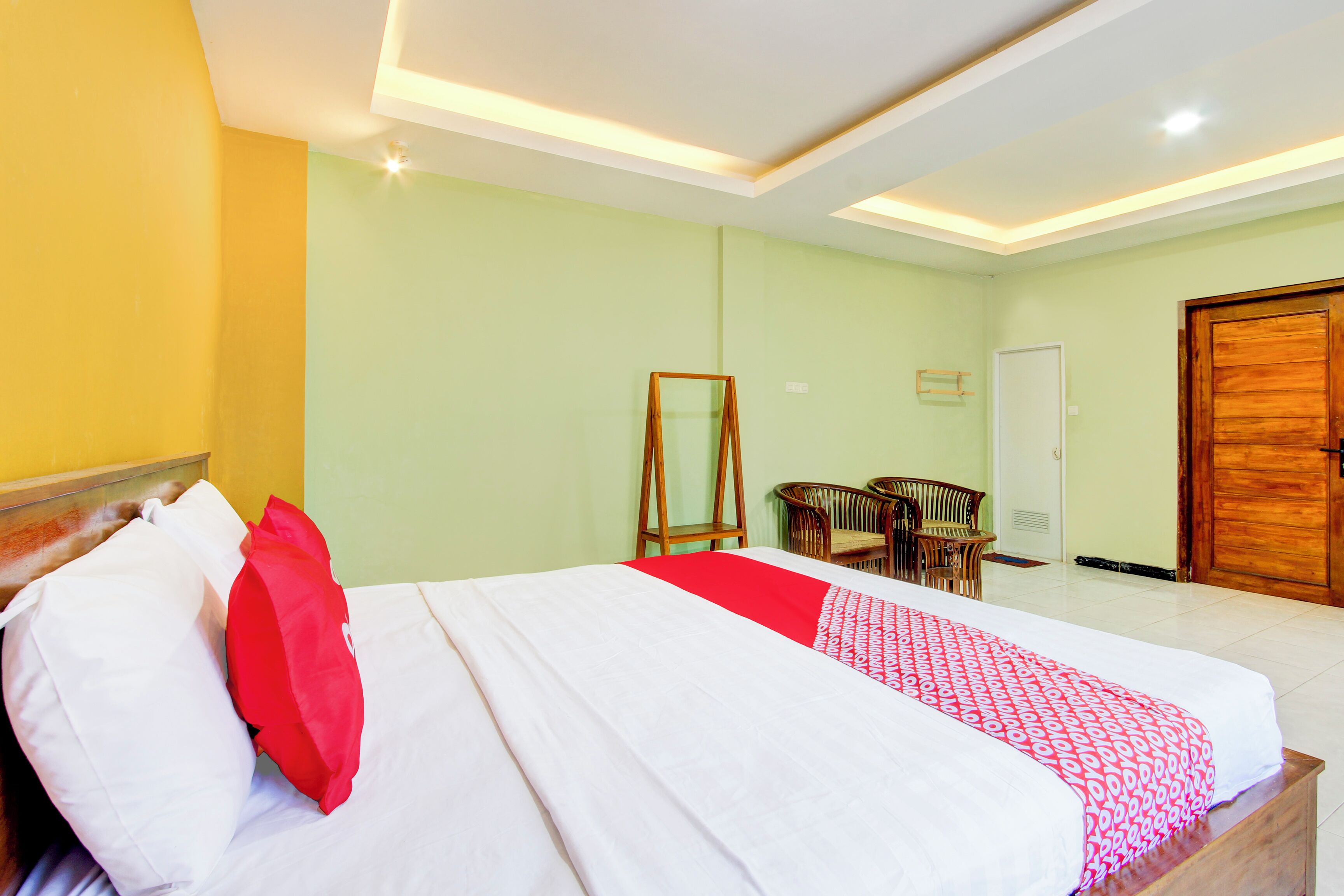 Una habitación de hotel con una cama, un armario de madera, un espejo y una silla.