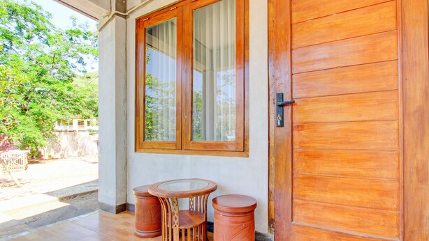 Une porte en bois avec un vitrage, une petite table ronde avec une chaise, et deux tabourets cylindriques.