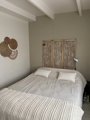 Een slaapkamer met een groot bed, een hoofdbord met bladmotieven en een decoratief object aan de muur.