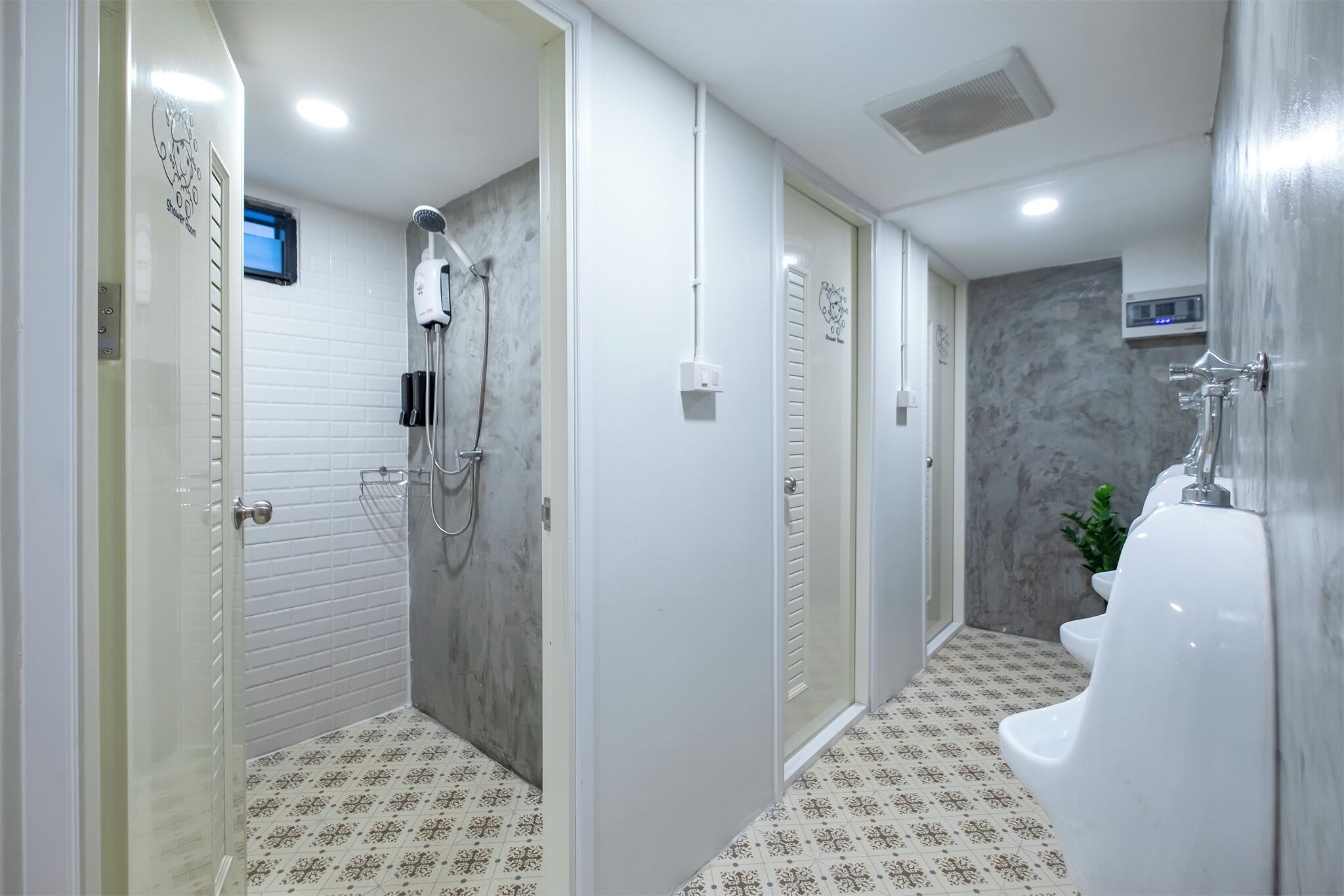 Un baño moderno con ducha, inodoro y orinal.