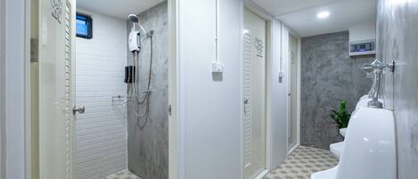 Un baño moderno con ducha, inodoro y orinal.