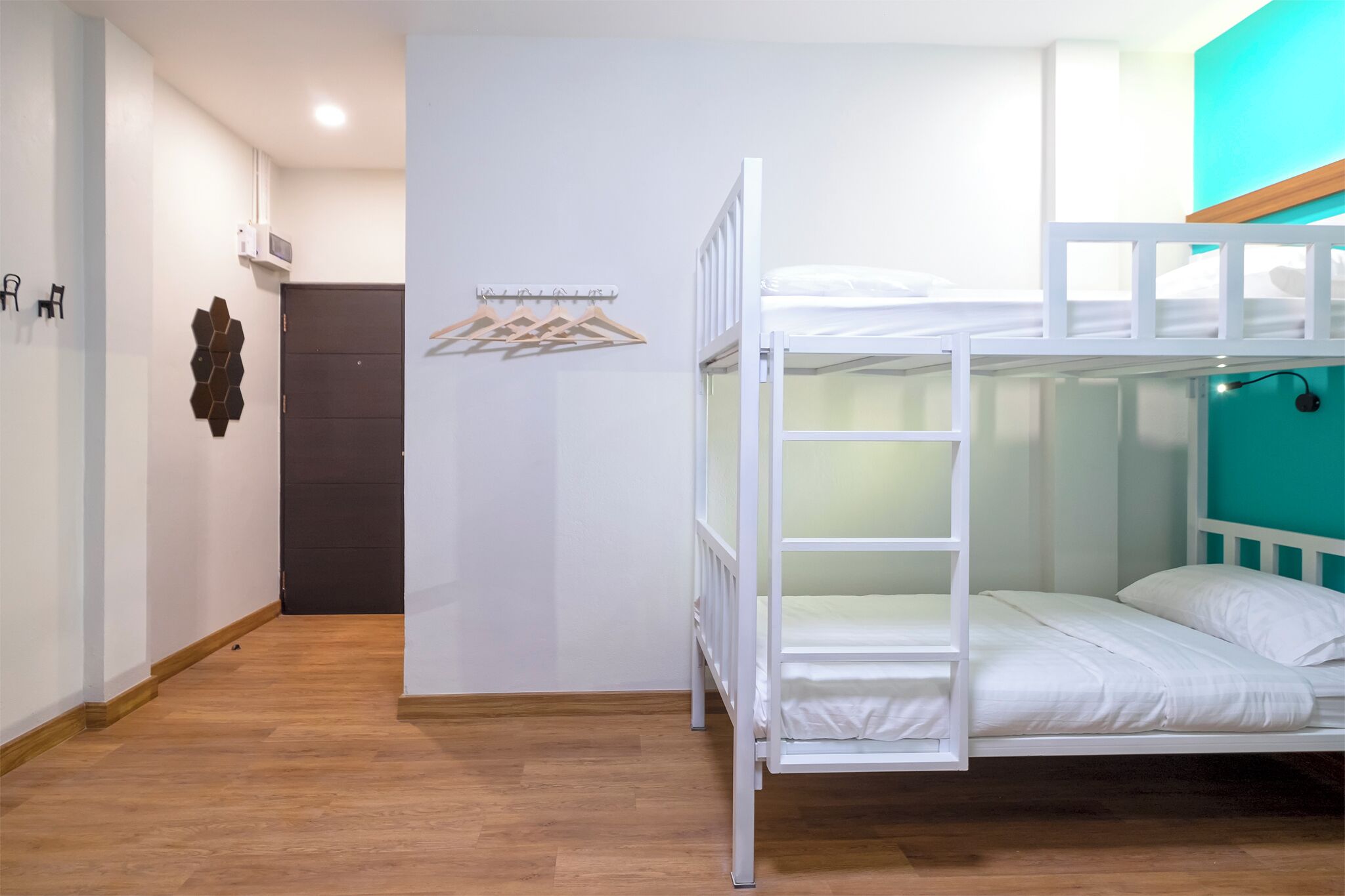 Una habitación con literas, suelo de madera, aire acondicionado de pared y una puerta.