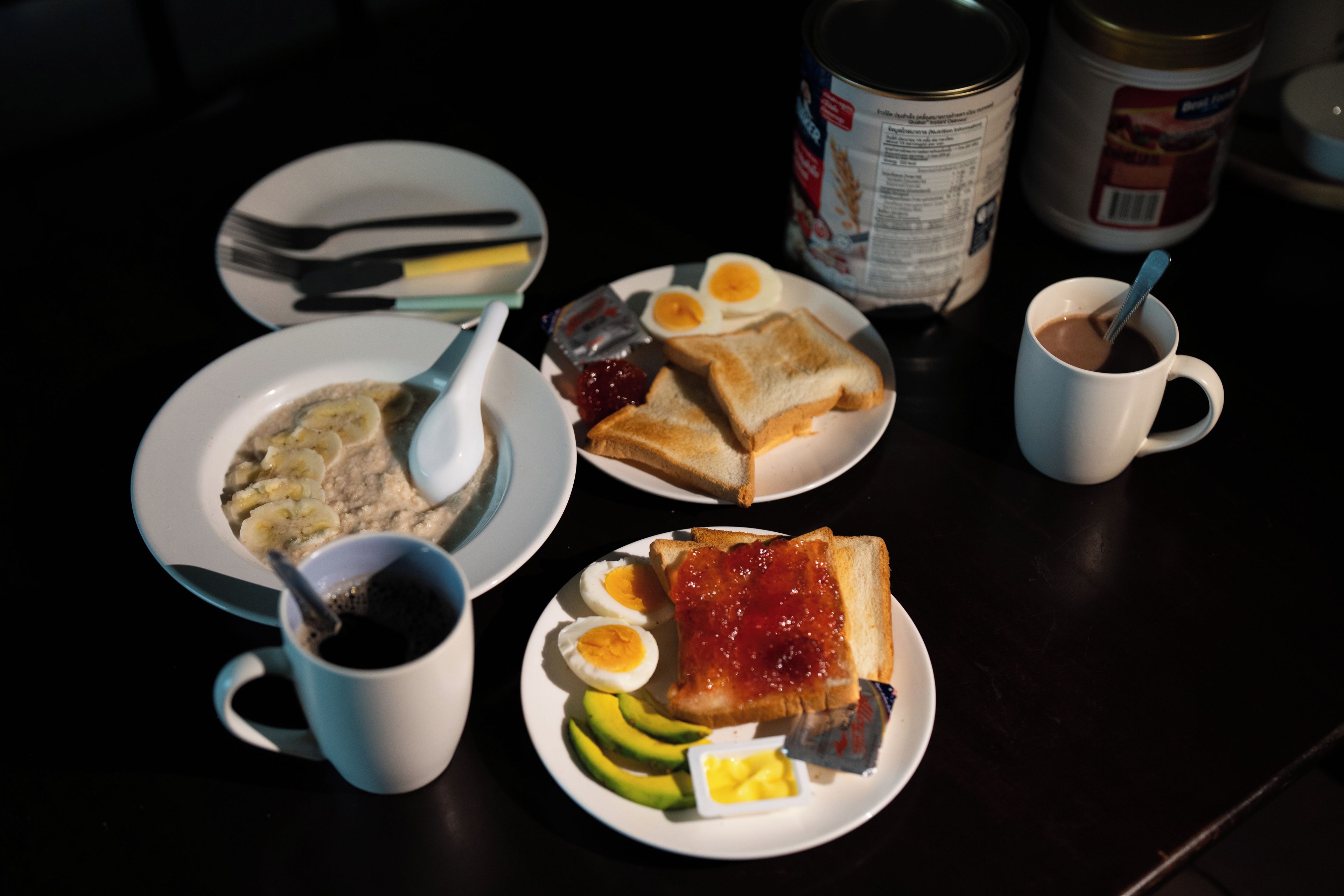 A breakfast setting with plates of food, a coffee cup, and a can of condensed milk.