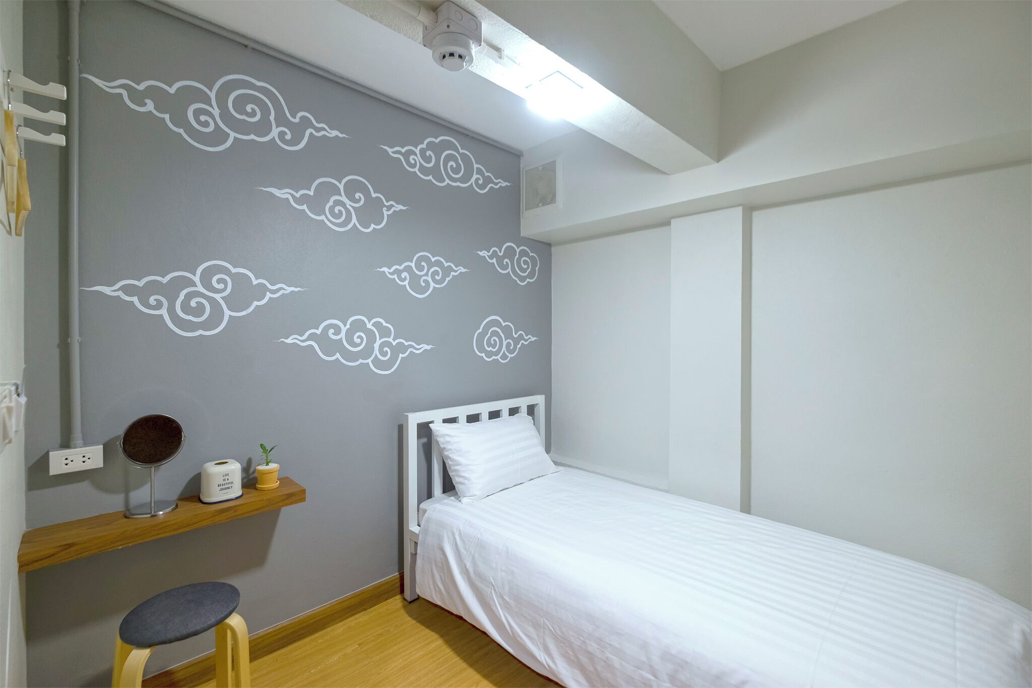 Una camera da letto con un letto, un comodino, uno specchio e una mensola con una pianta.