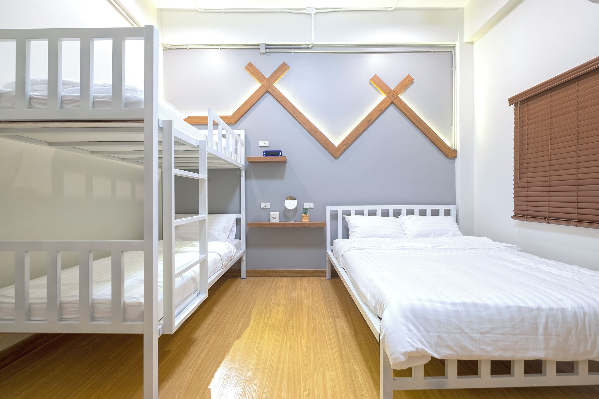 Une chambre avec des lits superposés, une table de chevet avec une lampe et une étagère fixée au mur.