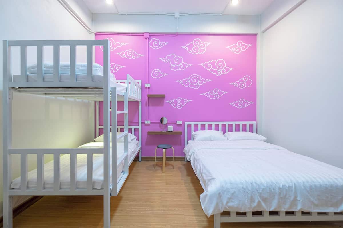 A bedroom with bunk beds, a desk, and a pink wall with cloud patterns.
