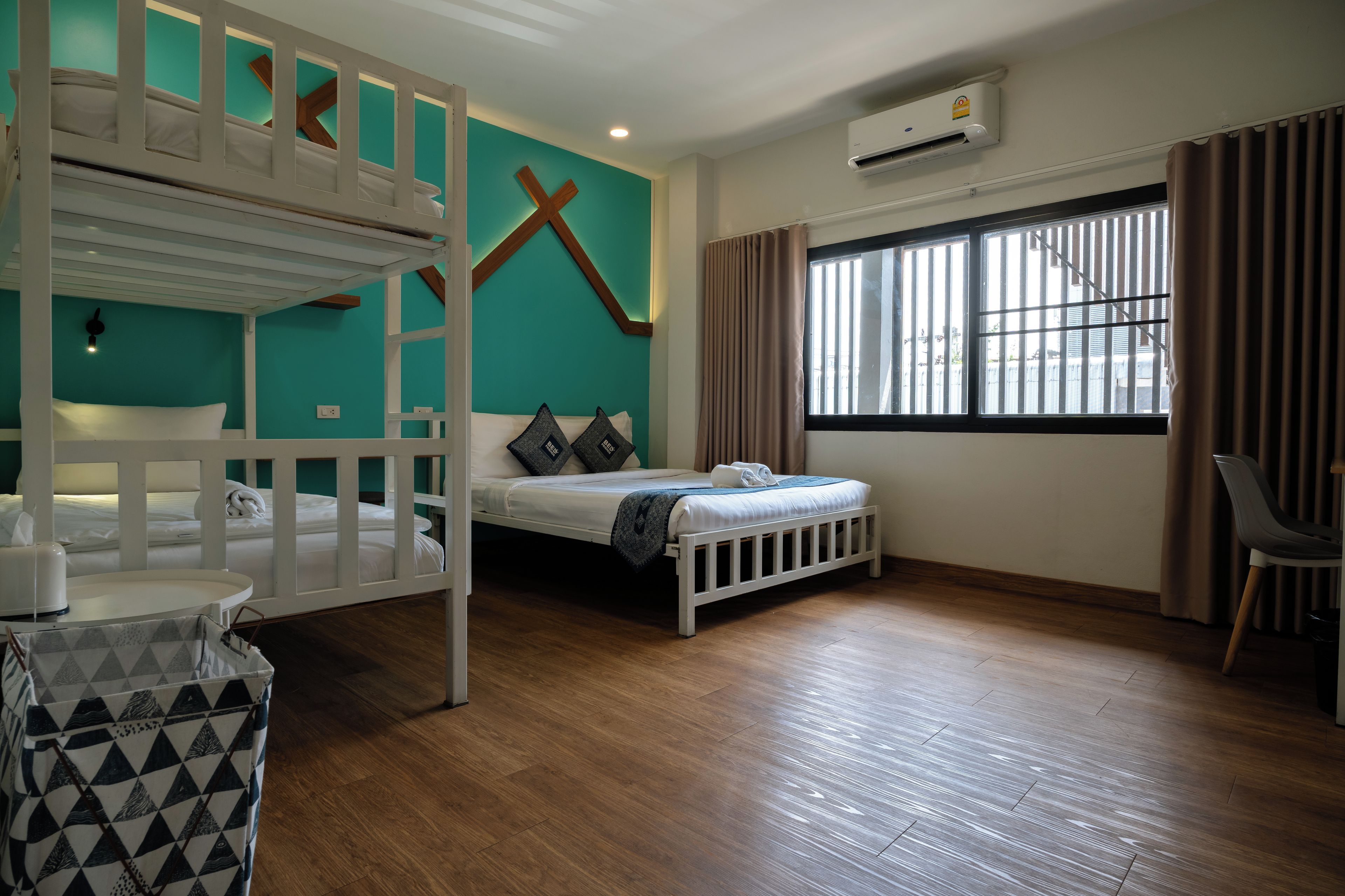 A room with bunk beds, a single bed, a window with curtains, an air conditioning unit, and a chair.