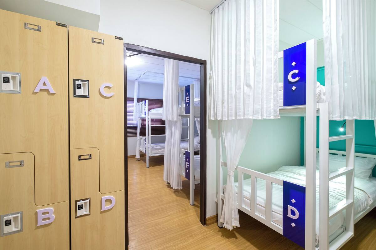 A children's room with bunk beds, a wardrobe with alphabet labels, and a door leading to another room.