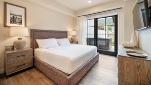 A bedroom with a large bed, wooden nightstands, a dresser, and a sliding glass door leading to an outdoor area. - Slopeside Retreat | Includes Two 1-Day Lift Tickets (Tamarack)