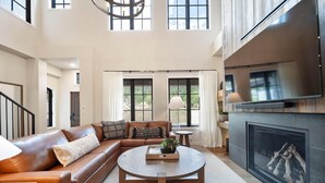 A spacious living room with a leather sofa, a round coffee table, and a fireplace. - Slopeside Retreat | Includes Two 1-Day Lift Tickets (Tamarack)