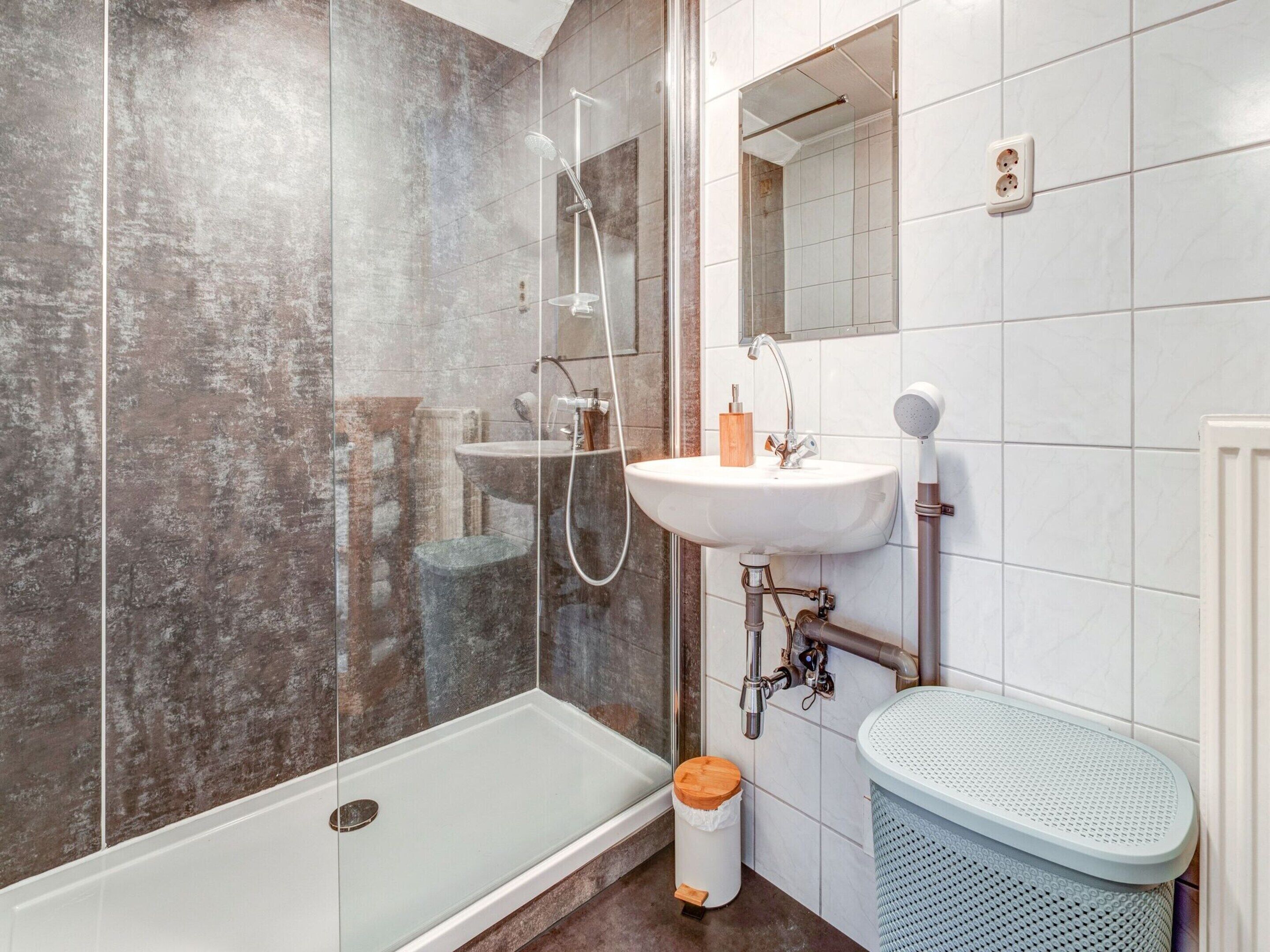 A bathroom with a glass-enclosed shower, a pedestal sink, and a toilet.