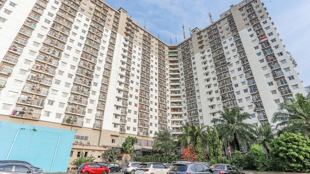 A high-rise residential building with multiple balconies and a parking area in front. - OYO 94117 Mr Rooms Appartement Mutiara (Bekasi)