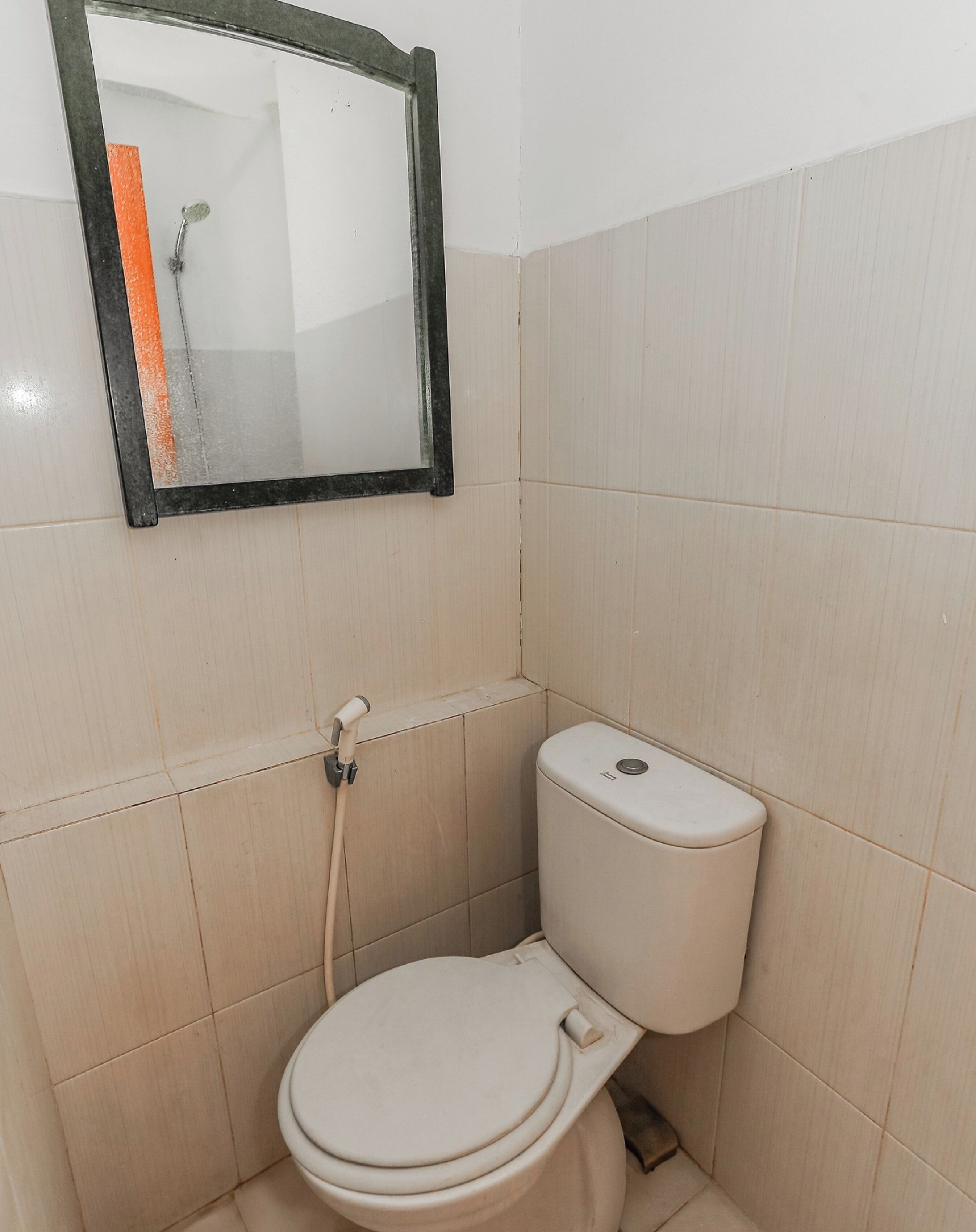 Et lille, rent badeværelse med toilet, spejl og brusebad.