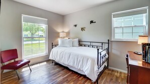 A bedroom with a bed, two windows, a chair, and a desk. - Retro Refuge On Woodstock Dr. (Van Wert)