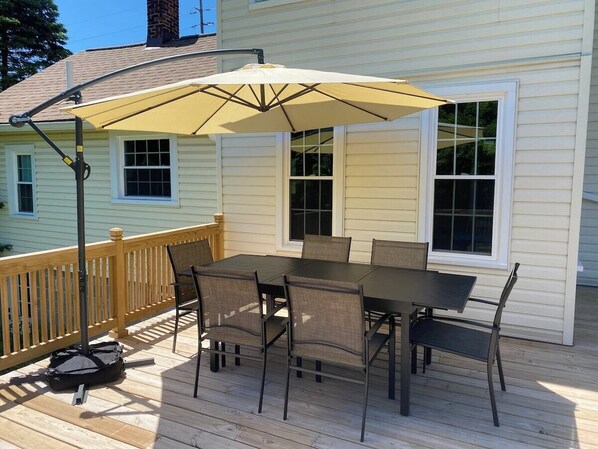 Une terrasse avec une table et des chaises, un parasol et une rambarde.