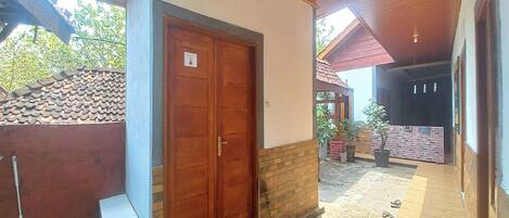 Un espacio al aire libre techado con una puerta de madera, un pequeño banco y una planta en maceta.