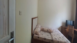 A bedroom with a bed, a wooden nightstand, a television, and a wooden chair. - Hotel O Homestay Gua Pindul Kang Haris (Karangmojo)