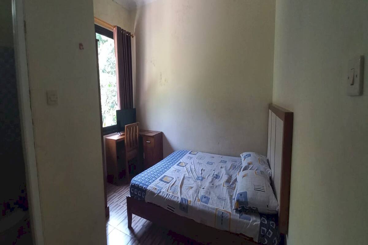 A bedroom with a bed, a desk, and a window with curtains.