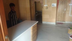 Uma área de recepção de hotel com balcão, placa de 'Não Fumar' e uma porta que dá para um quarto.
