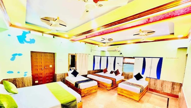 Quarto de hotel com duas camas, piso de madeira, uma porta e uma janela.