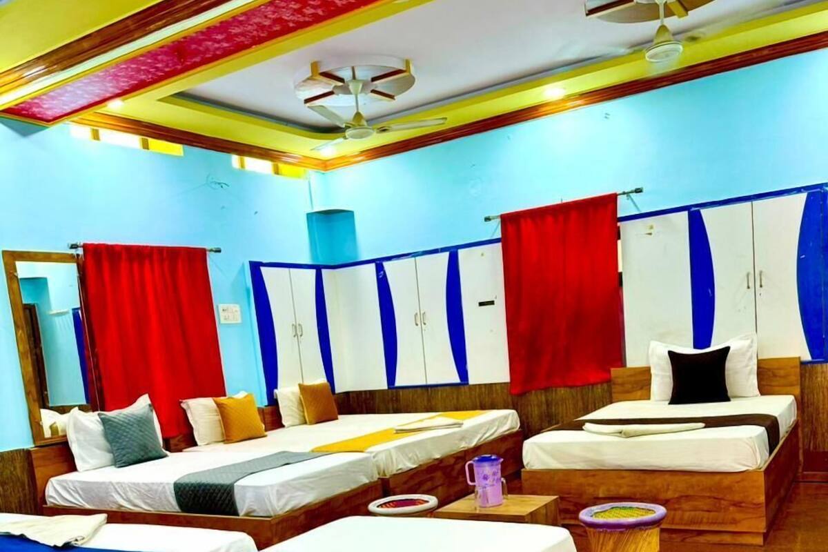 A hotel room with two beds, a wooden floor, and a ceiling fan.