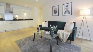 Ein modernes Wohnzimmer mit einem Glastisch, einem grünen Sofa und einer Stehlampe.