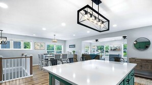 A spacious kitchen with a large island, wooden flooring, and modern pendant lighting. - The Lake Shack Waterfront Life (Camdenton)