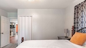 Une chambre à coucher avec un lit, une table de chevet, une lampe et un rideau à motifs.