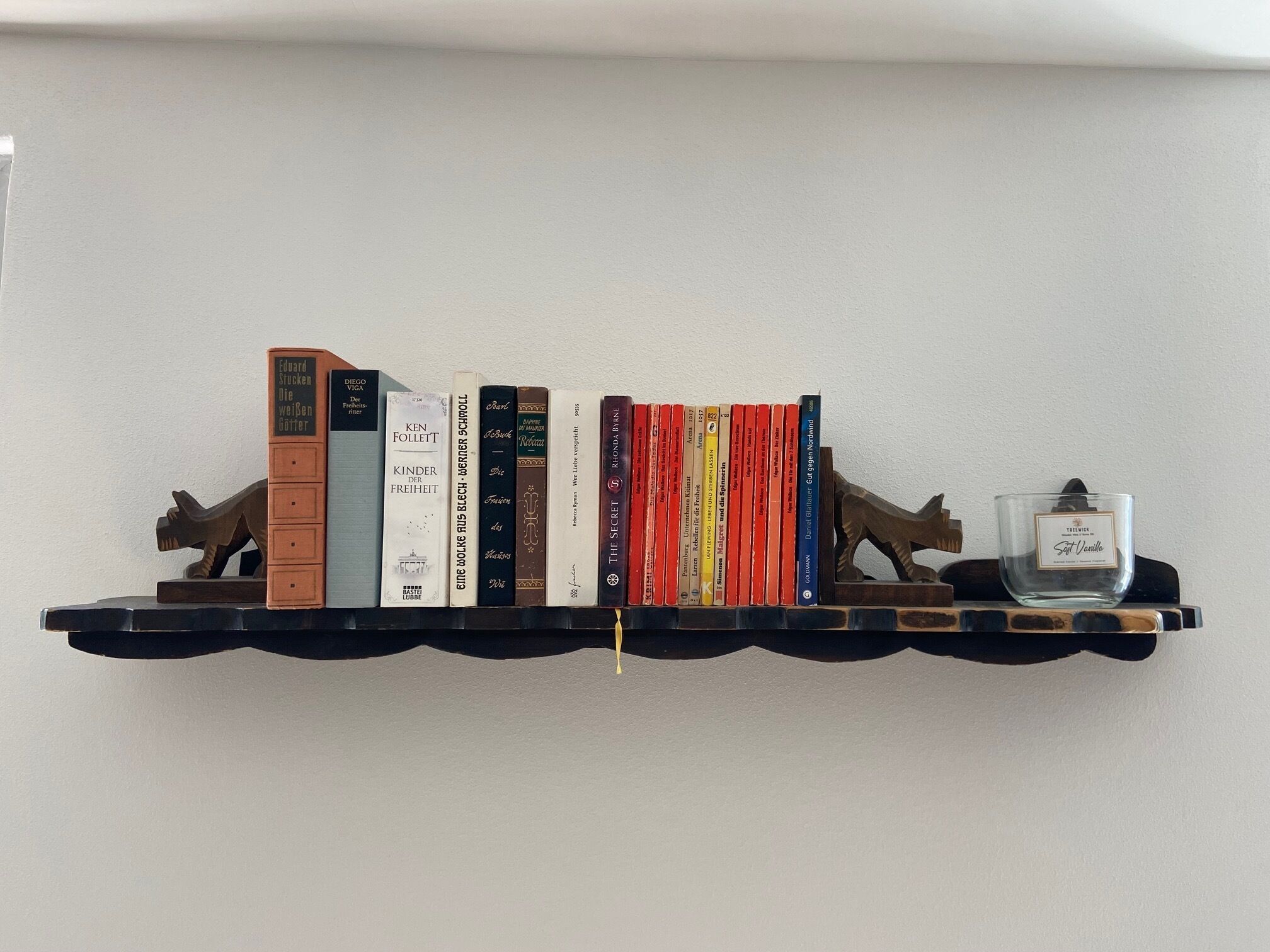 A bookshelf with books and a candle.
