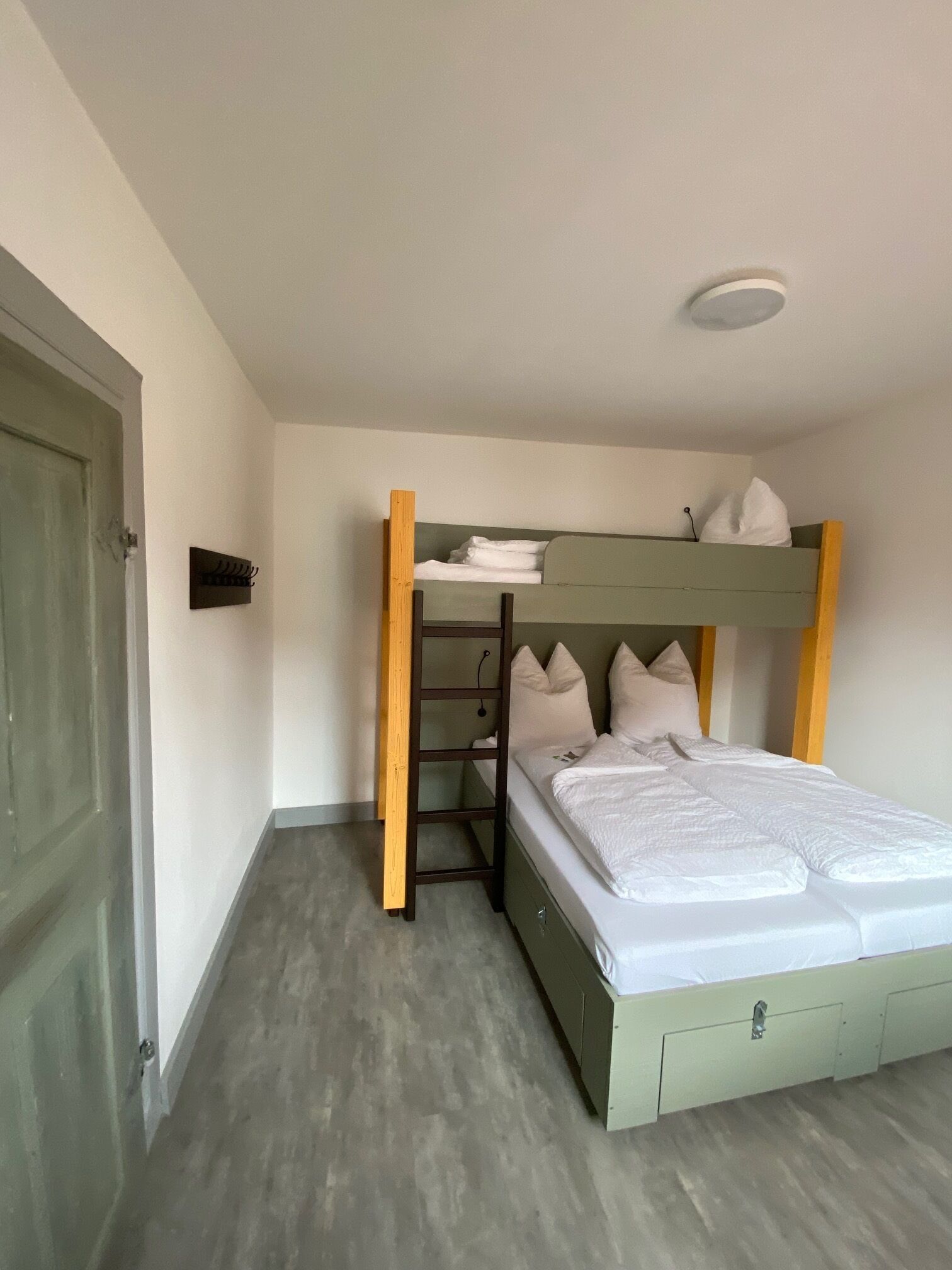A bunk bed with a ladder, a small shelf, and a bedside table.