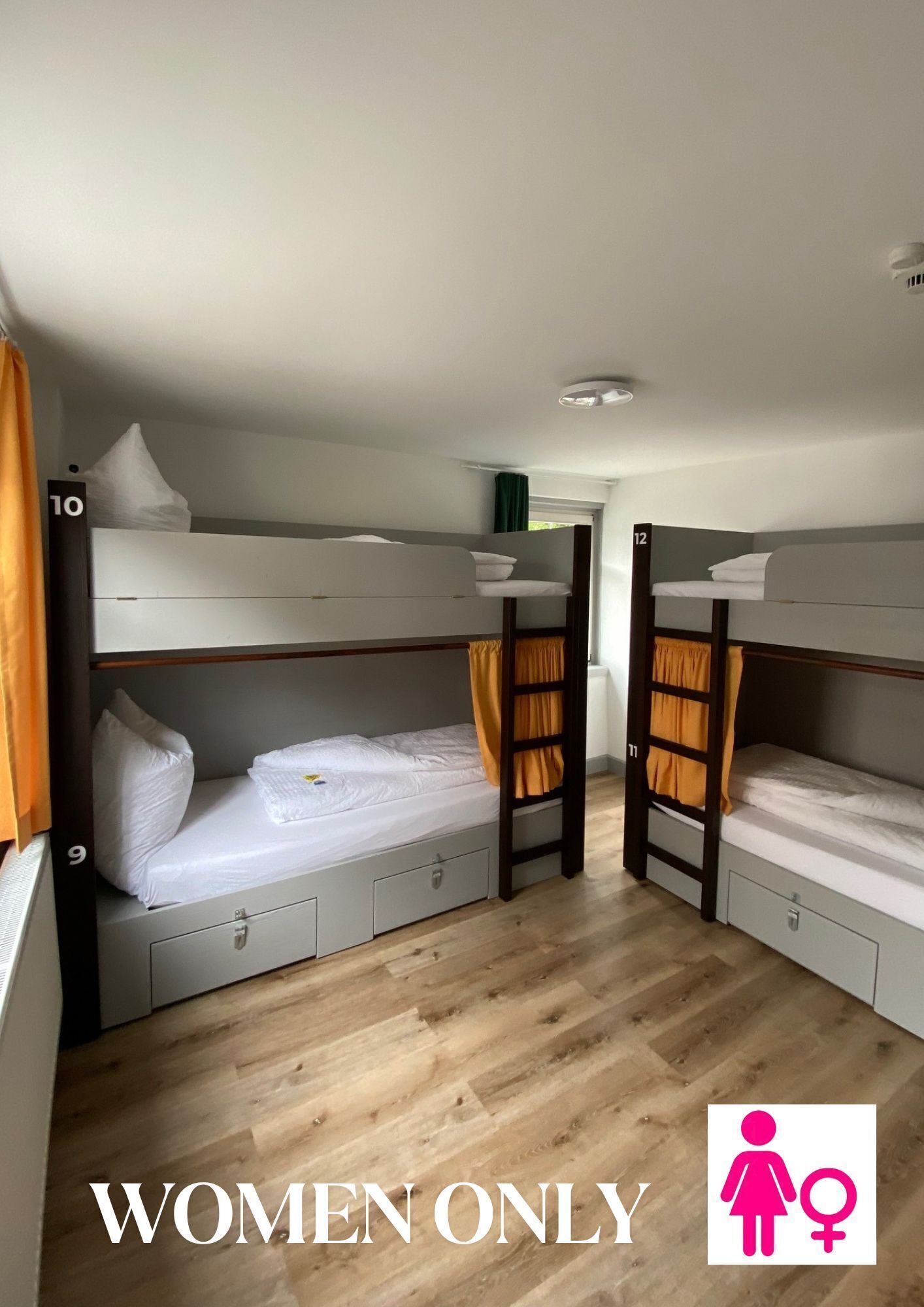 Dormitorio exclusivo para mujeres con literas, cada una con un cajón pequeño y una almohada.
