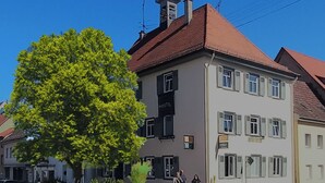 A two-story building with a red-tiled roof, a sign reading "Hoste" on the facade, and a large tree in front. - Hostel  Altes Spital Balingen (Balingen)