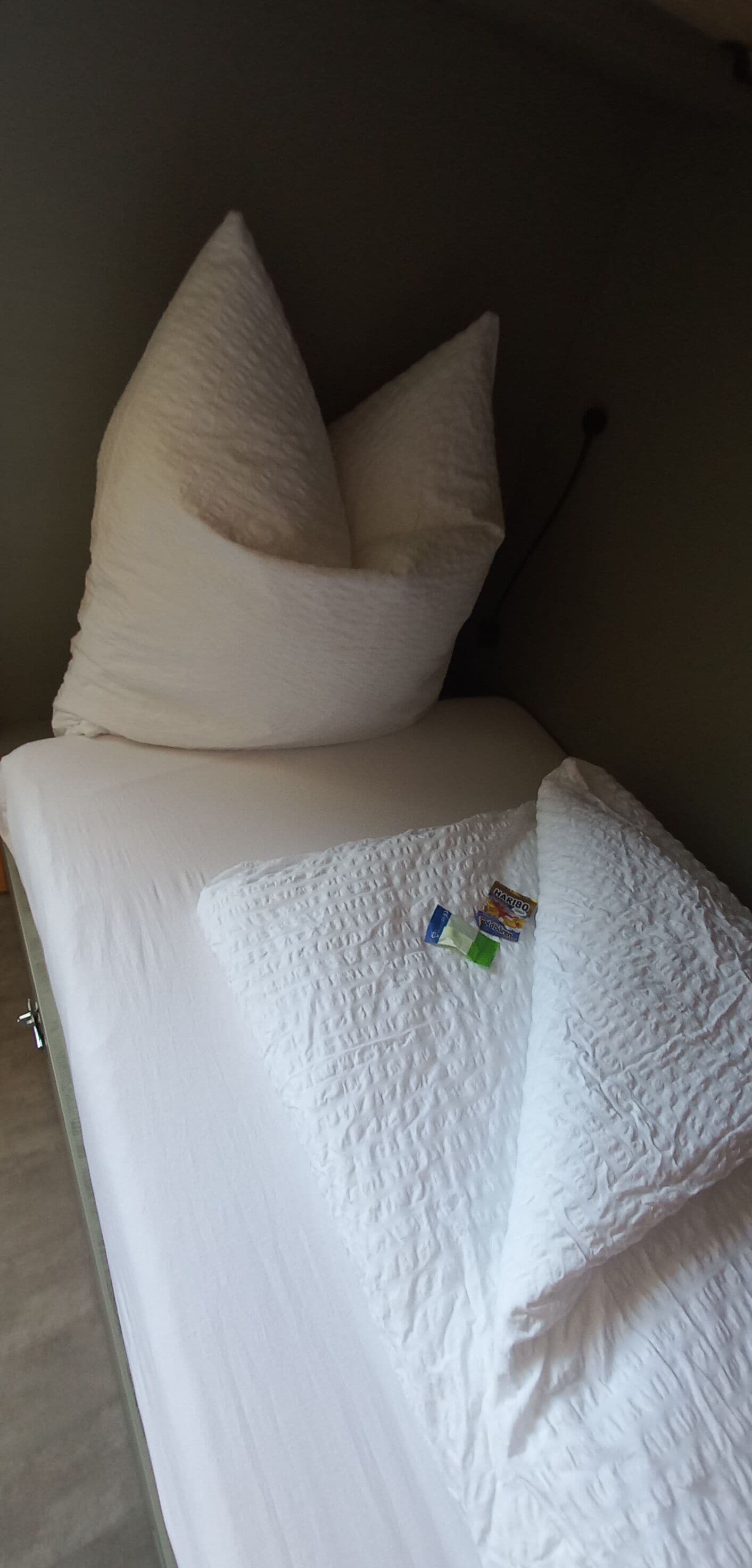 Una cama con ropa de cama blanca y dos almohadas.
