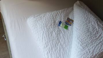 Una cama con ropa de cama blanca y dos almohadas.