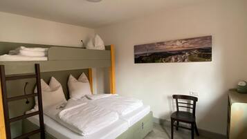 A bunk bed with a desk and chair, a painting on the wall, and a light switch.