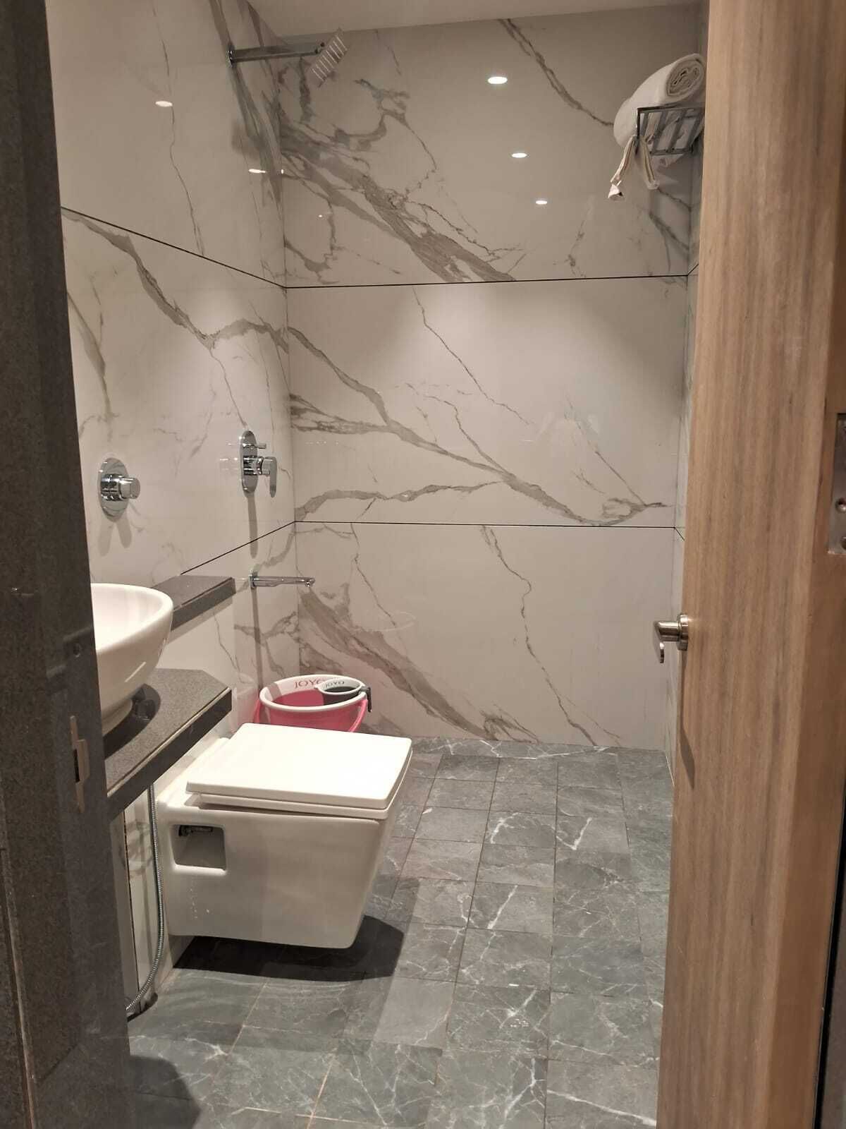 A bathroom with a marble wall, a toilet, a sink, and a shower area.