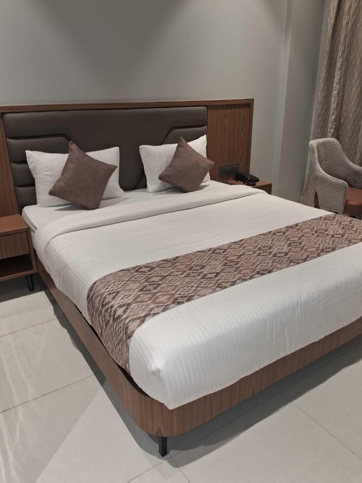Habitación de hotel moderna con una cama grande, cabecera de madera y una silla.