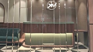 Un área de recepción con diseño moderno, que incluye un mostrador de recepción, un sofá verde y un suelo con estampado.