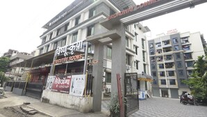 Un edificio de varios pisos con letreros que indican 'Vishnu Krupa Executive Rooms' y 'Broadway Commercial Center'.