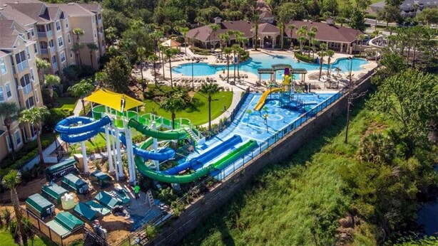 Een waterpark met meerdere zwembaden en glijbanen, omringd door woongebouwen.