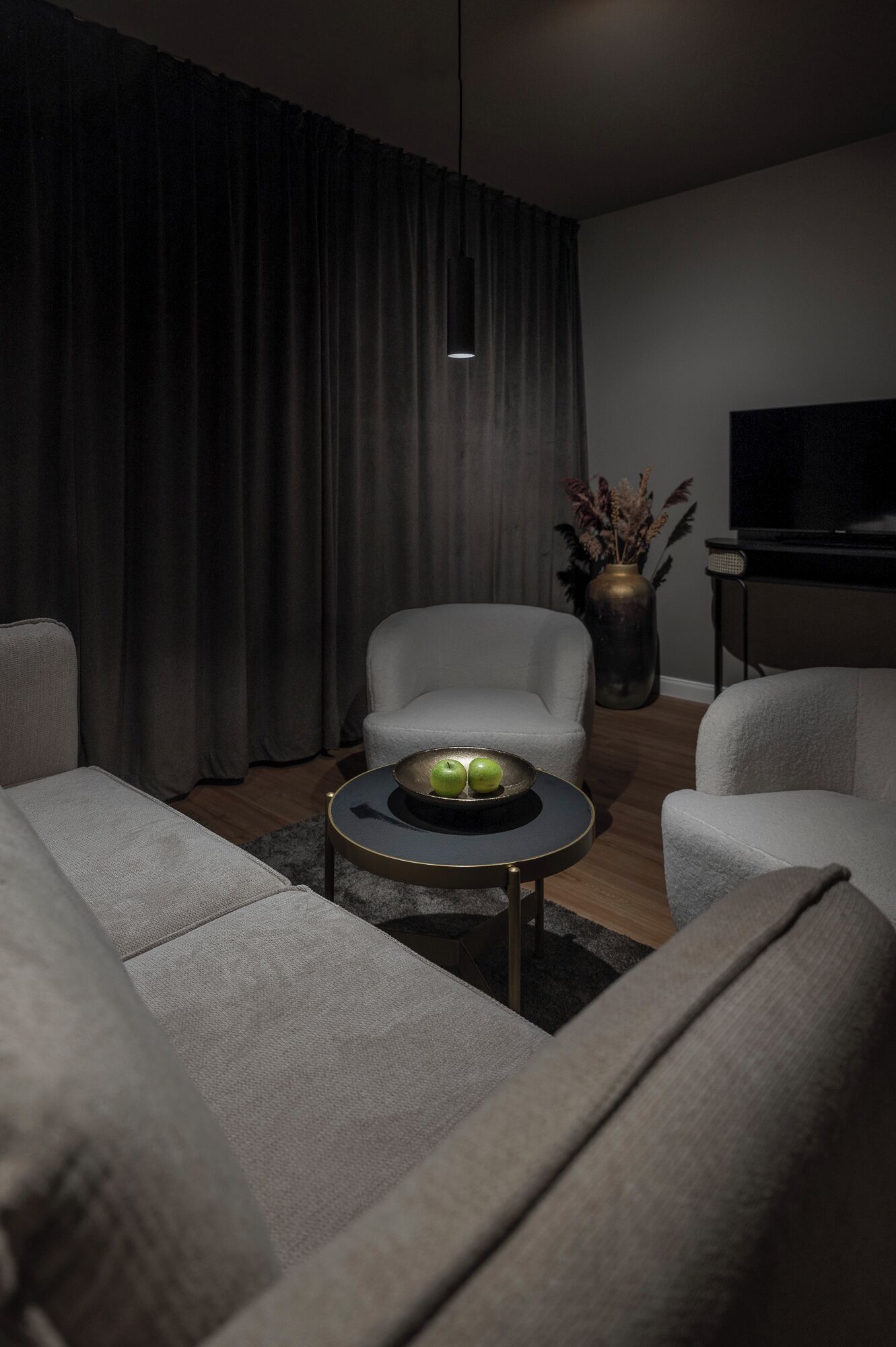 A modern living room with a sofa, armchair, and a coffee table with apples.