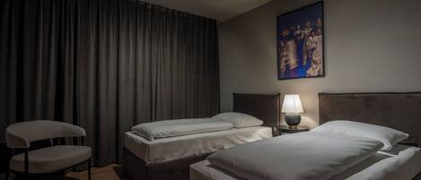 Habitación de hotel con dos camas, una silla, una lámpara y un cuadro en la pared.