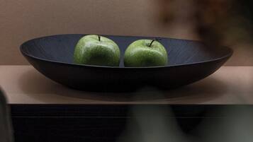A dark blue plate with two green apples on a wooden surface.
