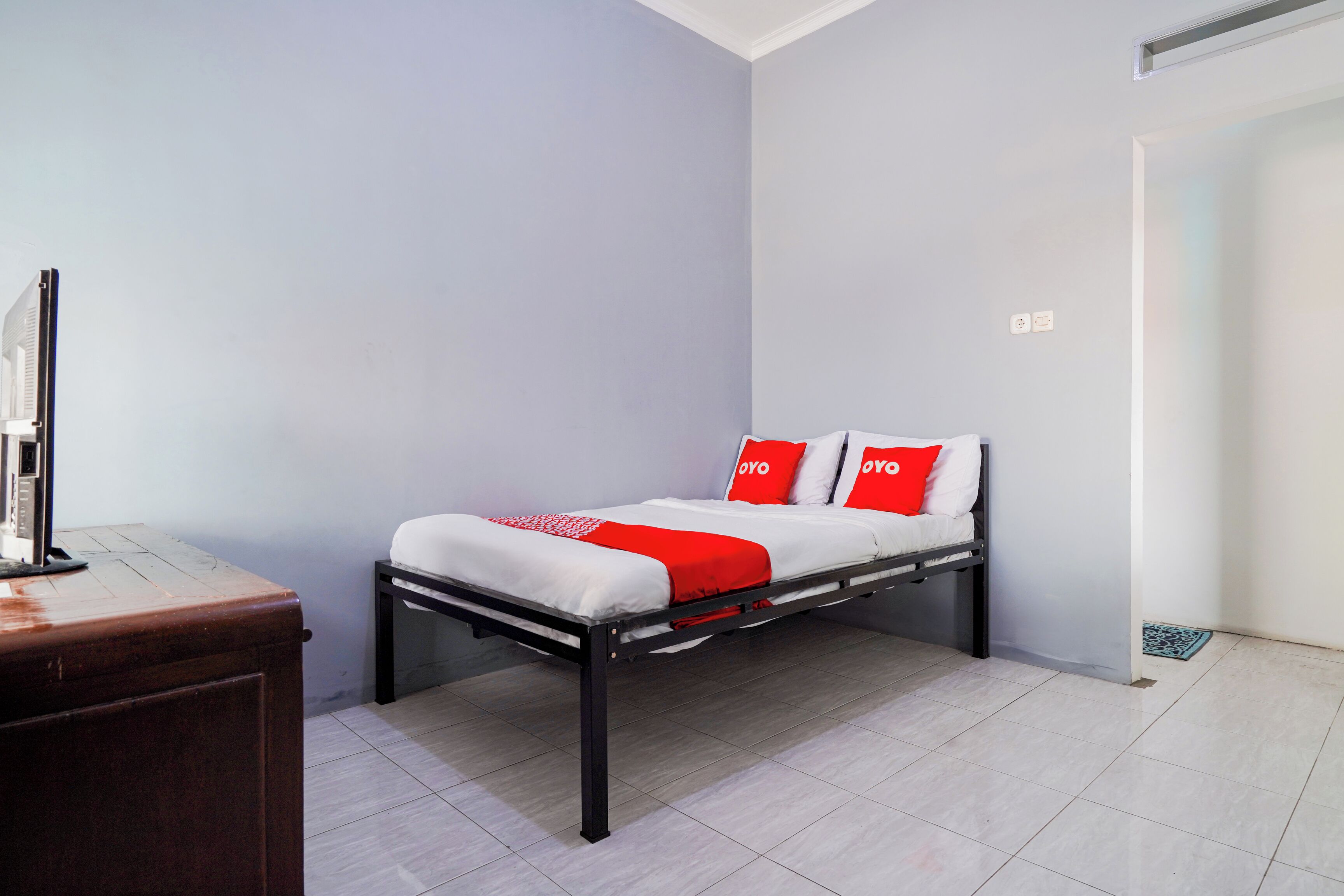 A small, neatly arranged room with a bed, a desk, and a chair.