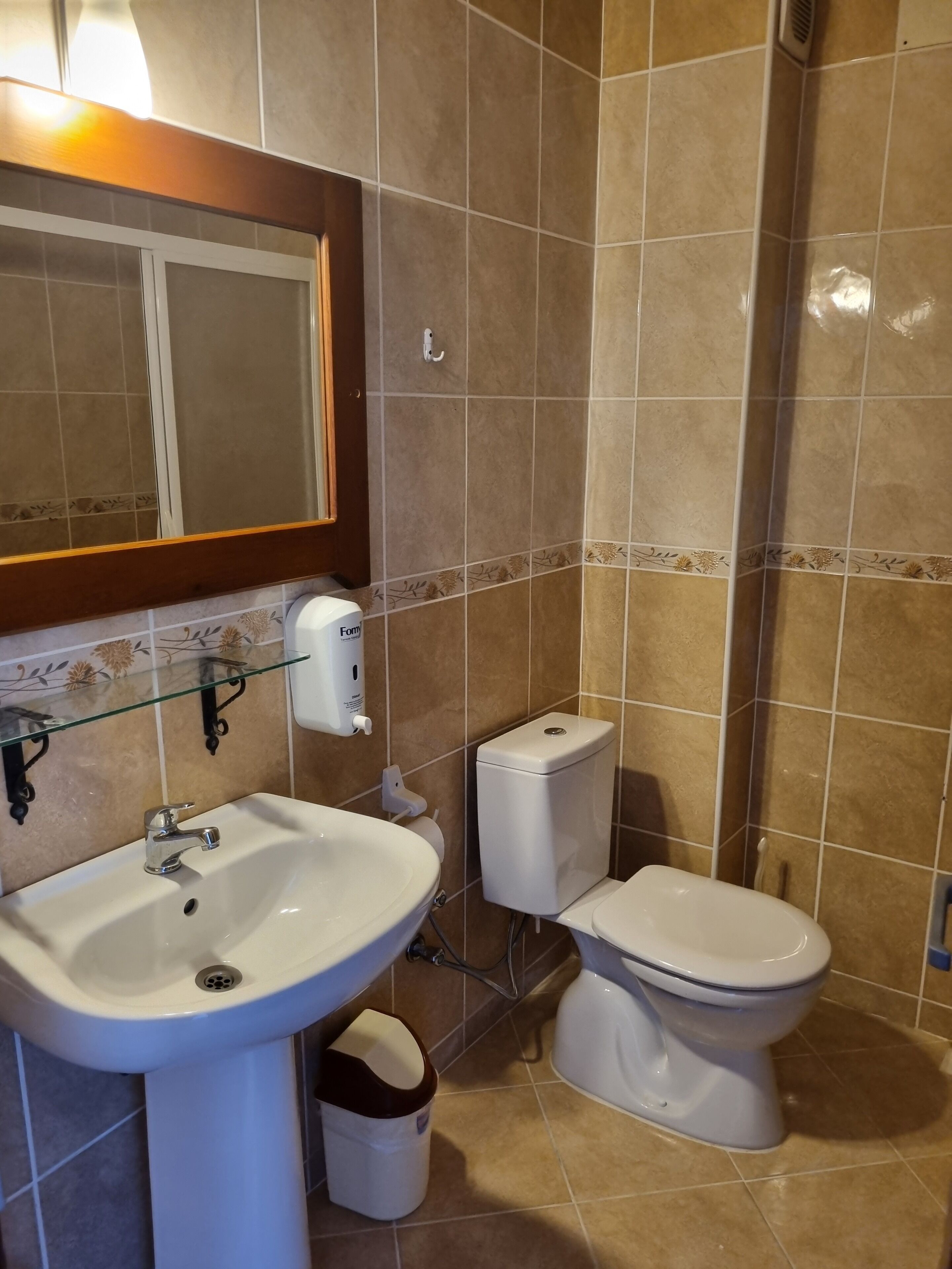 A bathroom with a sink, toilet, and hand dryer.