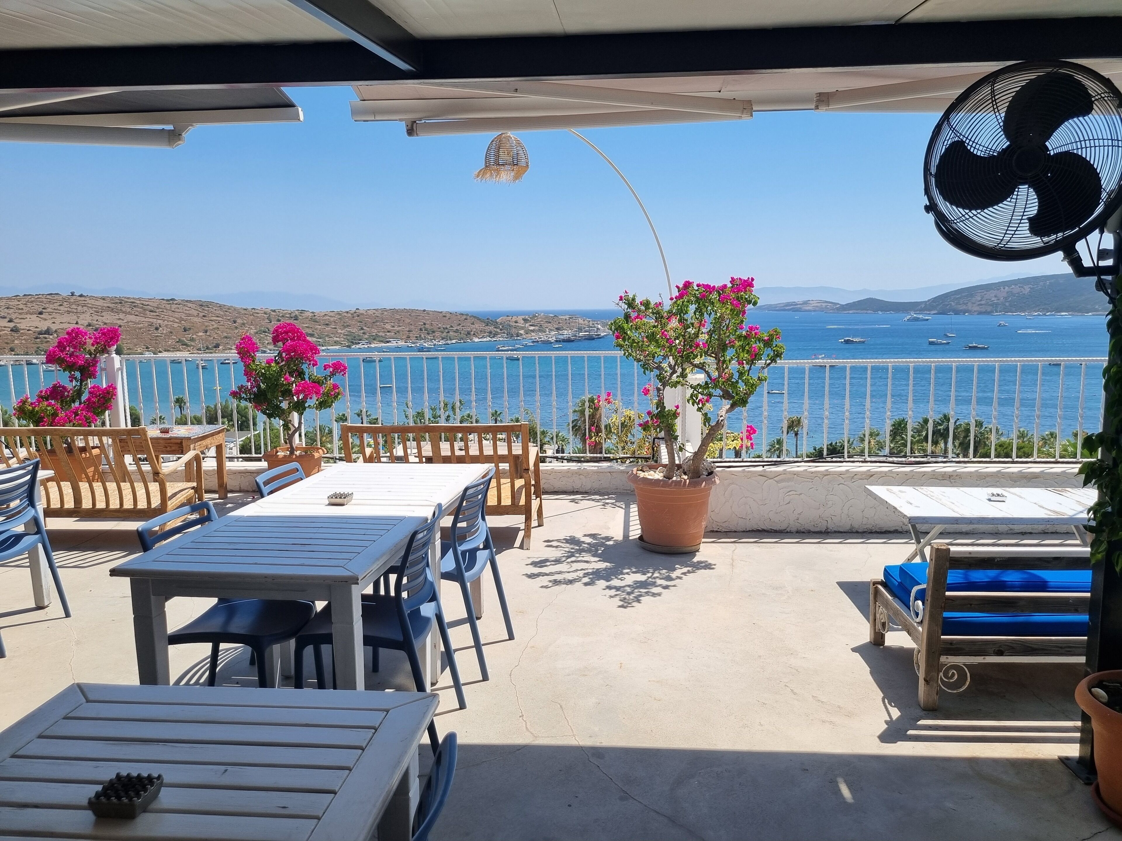 Terraza con mobiliario exterior, un ventilador y vistas al mar.