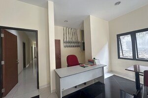 Una habitación con escritorio, silla, ventana y puerta.