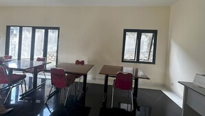 Un salón de conferencias con una mesa de vidrio, sillas rojas y dos ventanas.